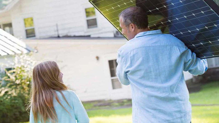 Girl beside man carrying solar panel