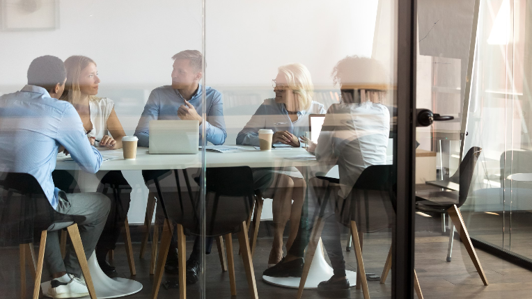a team sitting at a table around a computer