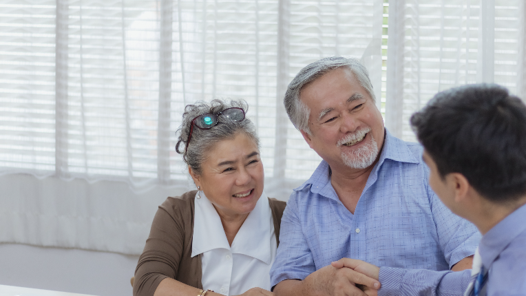 Old couple smiling while greeting their advisor.