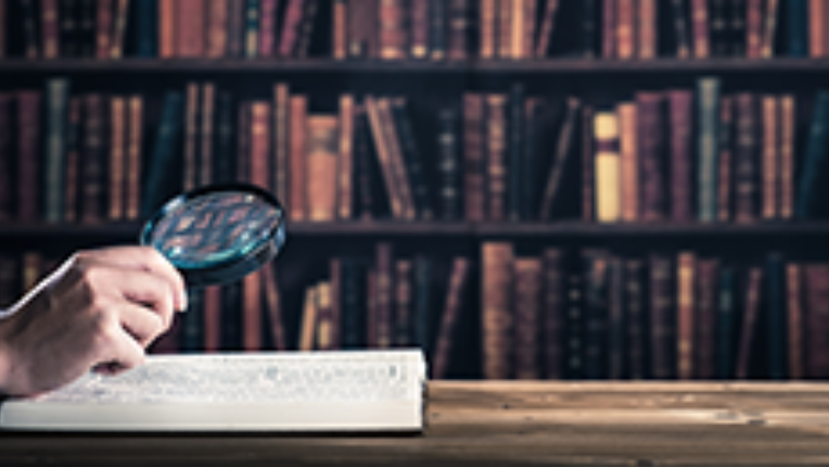 a person holding a microscope over a book