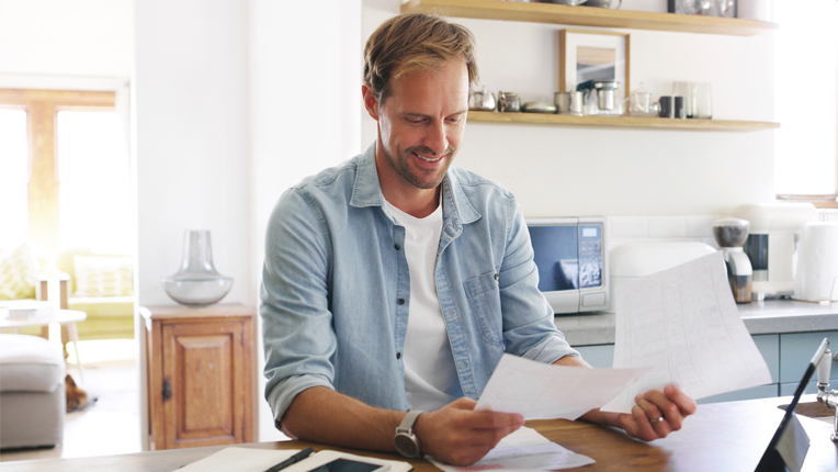 Man sitting at dining table reviewing financial statements