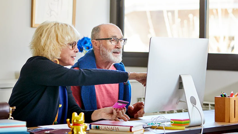 Woman and man at desktop computer with credit card in hand