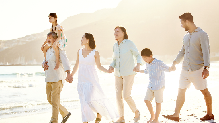 Happy family holding hands and walking along a beach.
