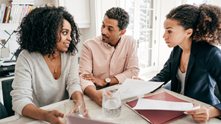 Un couple qui regarde un rapport mensuel sur les marchés mondiaux avec leur conseillère en placement