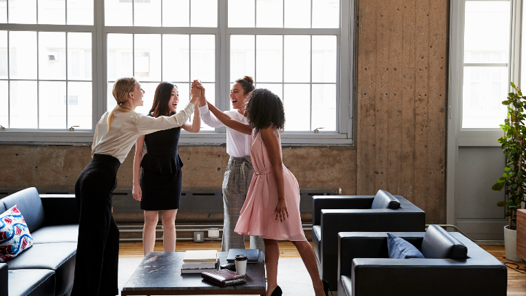 Women in an office high five each other