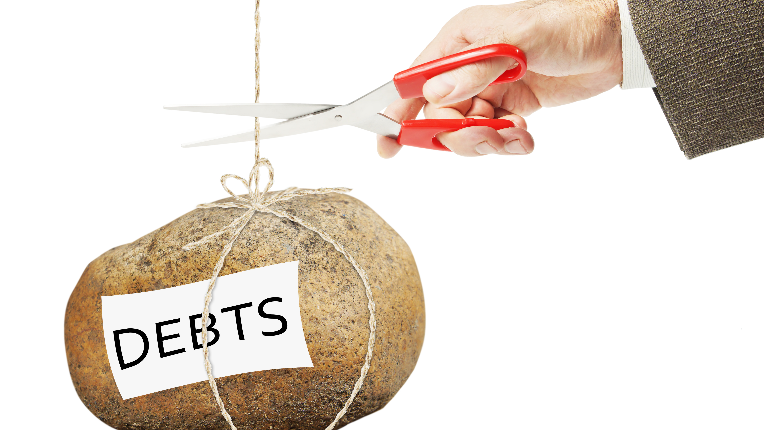 Picture of a hand with scissors cutting the string holding up a bag with debts written on it