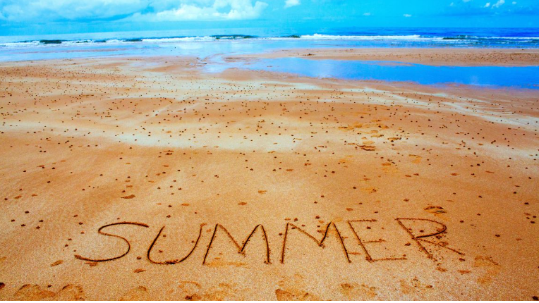 The word summer written on a sandy beach