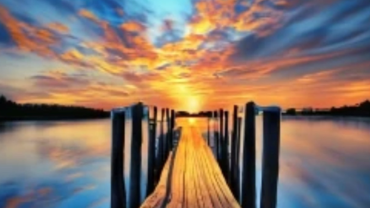A picture of a dock in a lake at sunset.