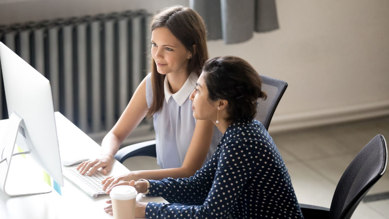 Deux femmes d’affaires travaillant et prenant un café tout en collaborant à un projet et en partageant un ordinateur.