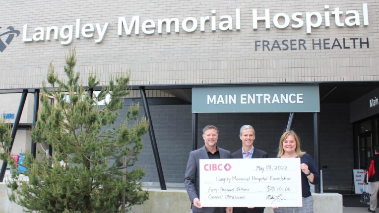 Three people holding a cheque