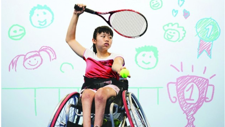 A woman in a wheelchair, playing tennis.