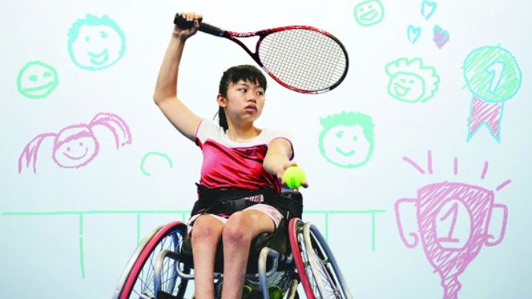 Une femme en fauteuil roulant, jouant au tennis.