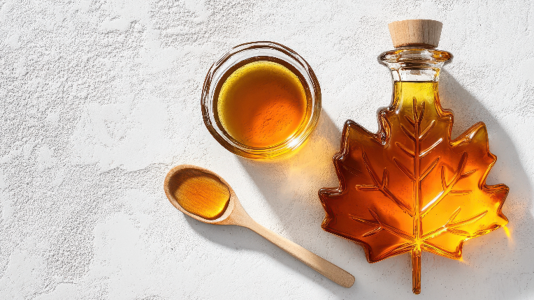 Maple syrup container and spoon on counter.