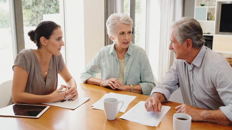 Three people are seated at a table, engaged in a discussion.