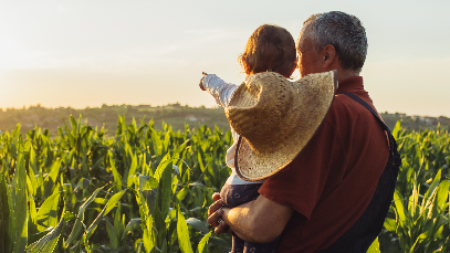 Man holding child looking over farm field