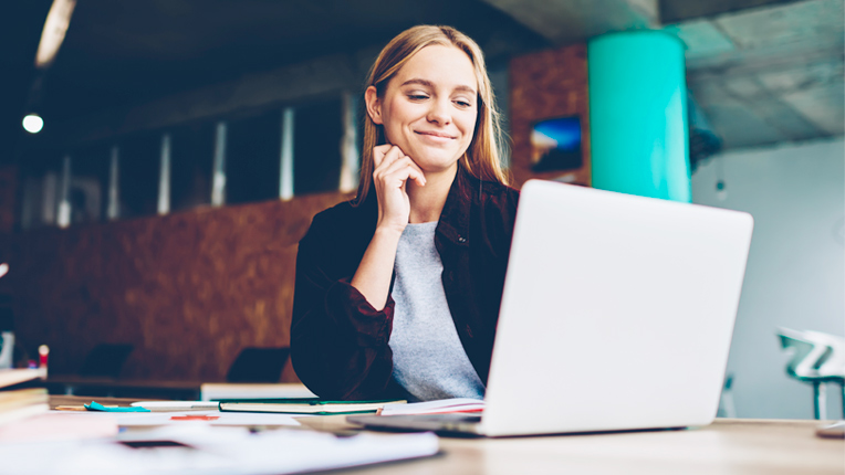 Photo of a successful female graphic designer watching tutorial about creative ideas on a laptop computer.
