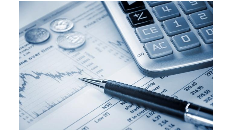 a pen, calculator and change on top of a spreadsheet in greyscale