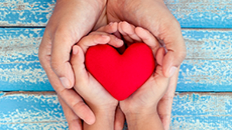 Two pairs of hands holding a heart