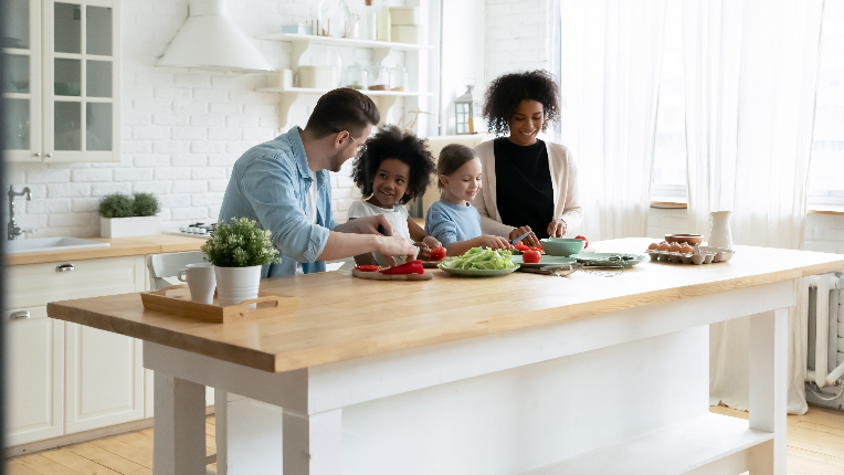 Happy multinational family with kids prepare vegetable salad in kitchen