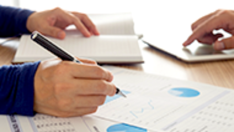 Person writing on papers covered with graphs