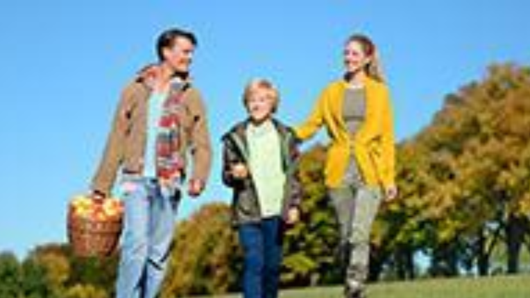Man holding a bucket of apples with a women and a child