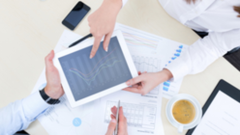 Two people reviewing a chart about investments on iPad.