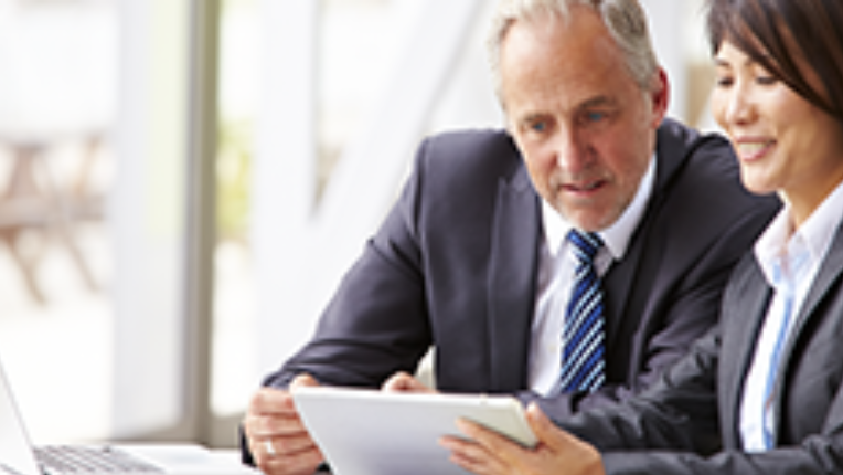 homme et femme en tenue professionnel regardent un portable et une tablette