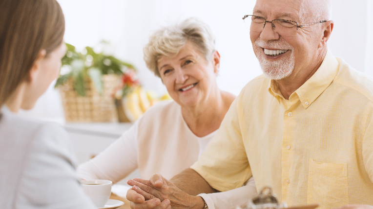A smiling married elderly couple holding hands.