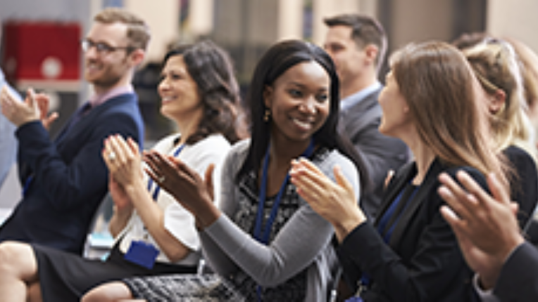 a group of people sitting in a conference and clapping