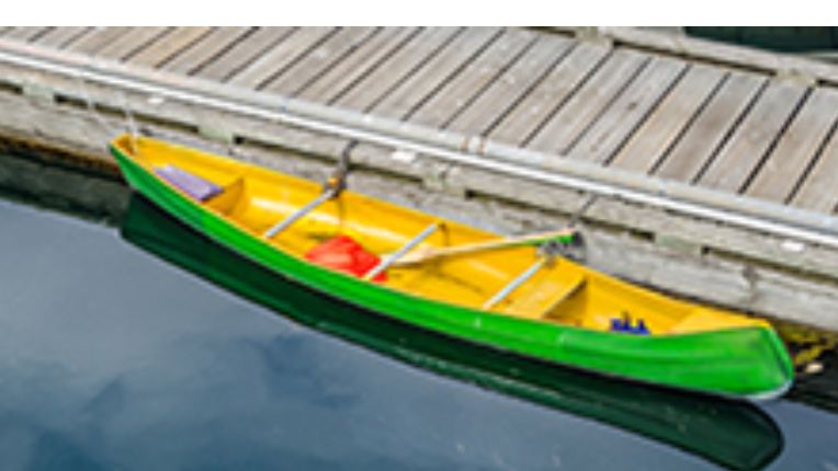 a canoe on water which is parallel to a wooden dock