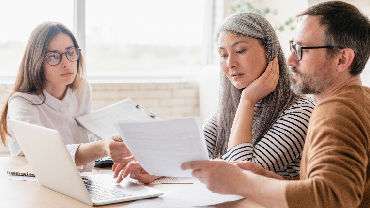 Middle aged couple reviewing documents with their advisor.