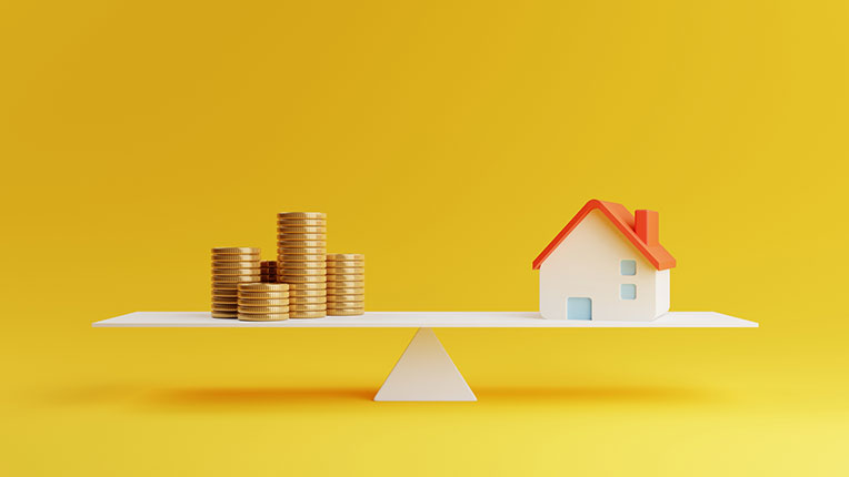 A balanced scale with a house on one end and coins on the other
