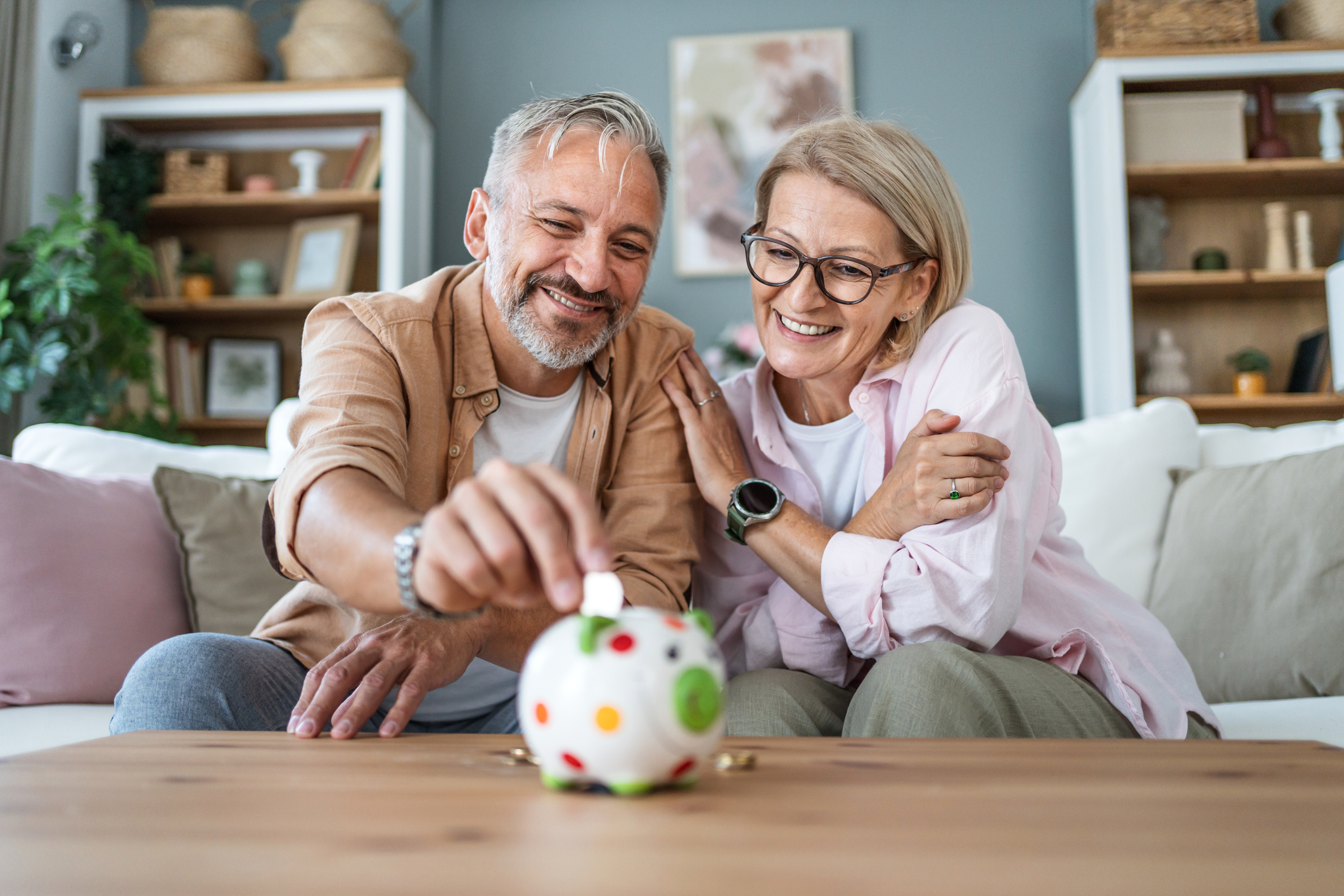 Retired couple putting coins in piggybank