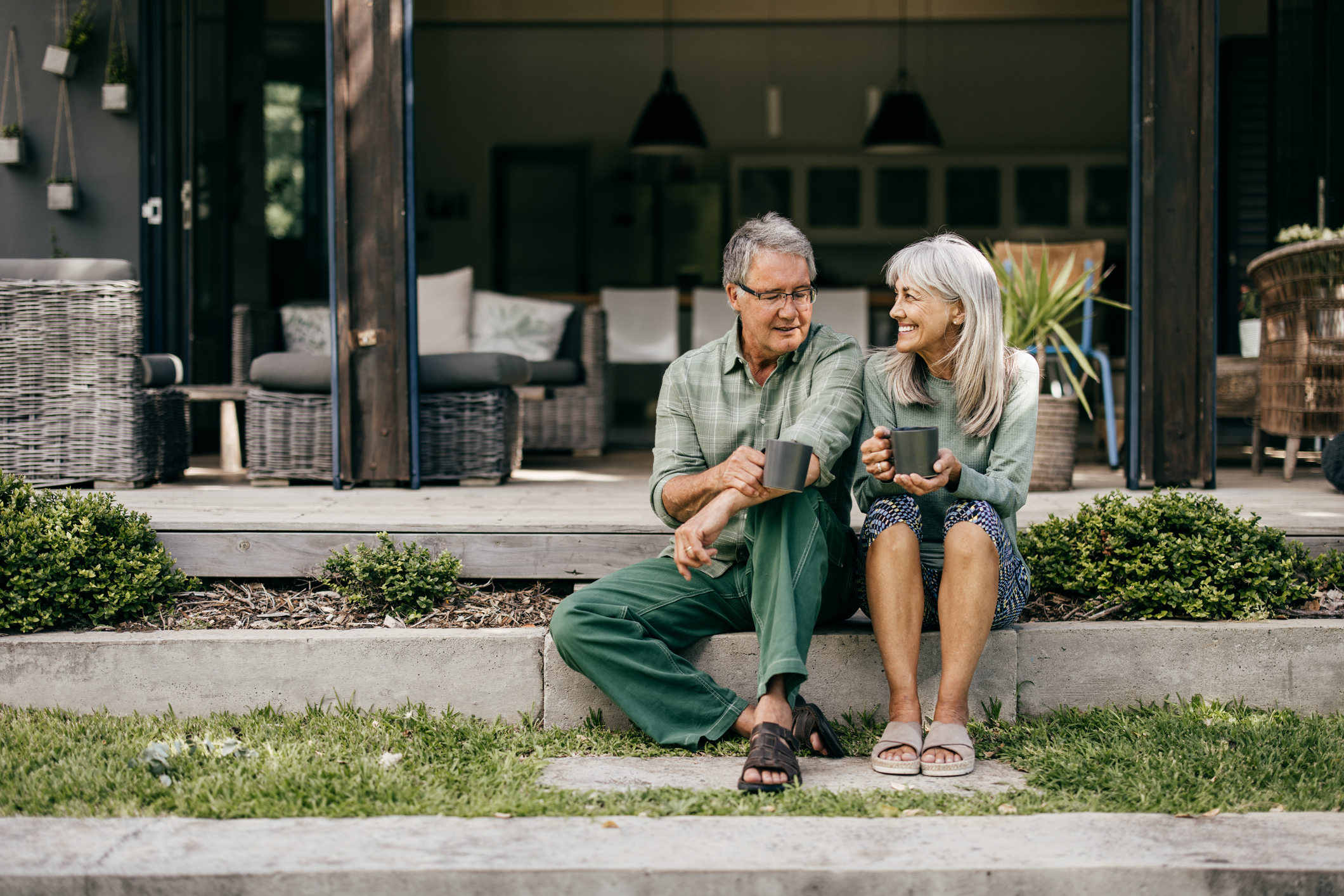 Retired couple sitting on porch drinking coffee