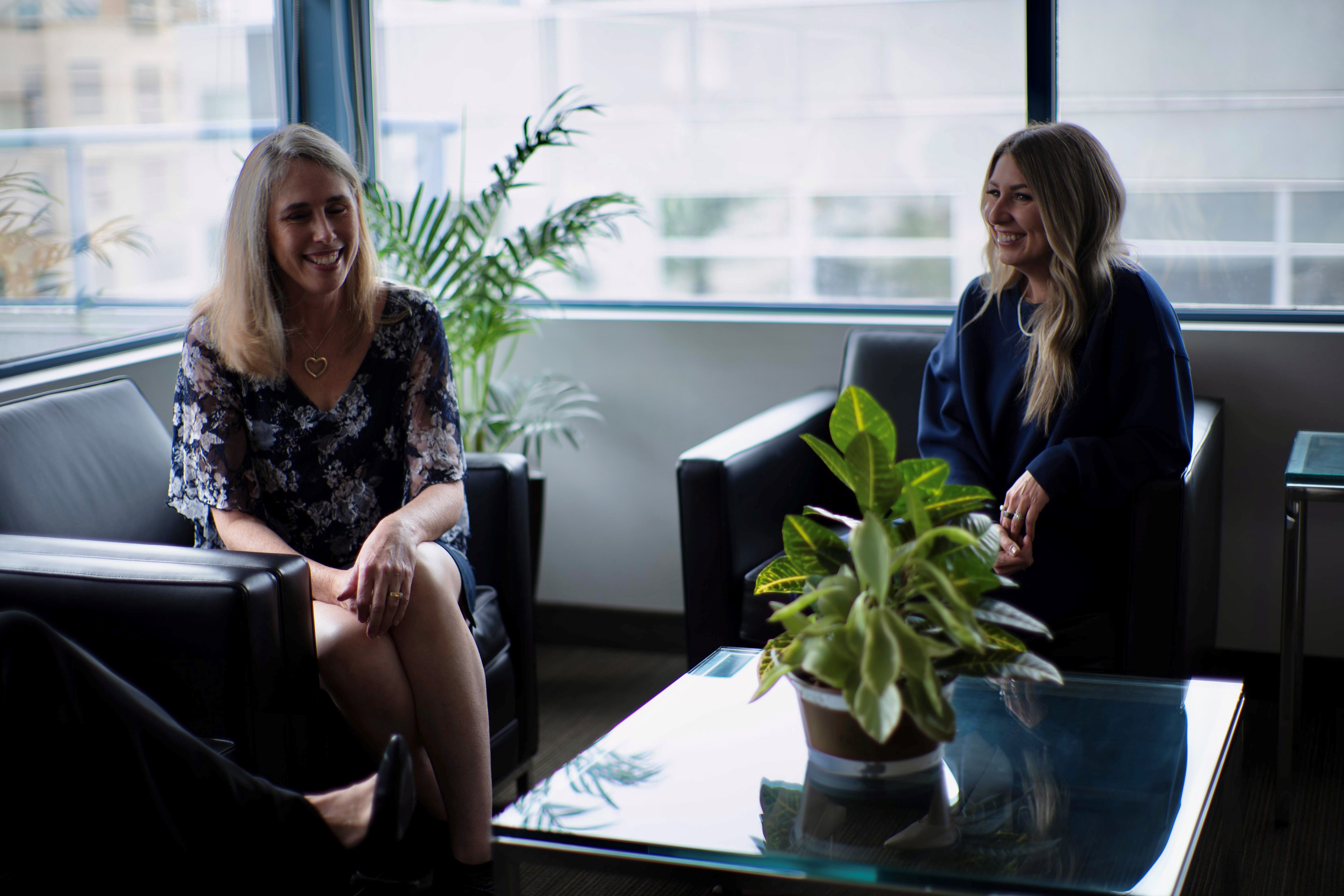 Laurie and Tracey sitting in boardroom chatting and smiling
