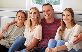 Image of a smiling family sitting together and watching an event