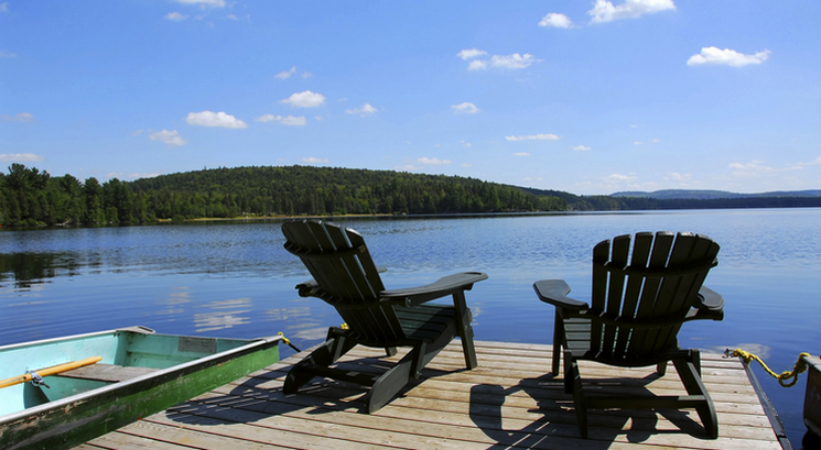 Scenic day view of two deck chairs overlooking a lake.