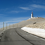 a coastal road with snow and a lighthouse.