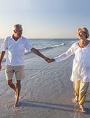 Man and woman holding hands walking in the sand by the water