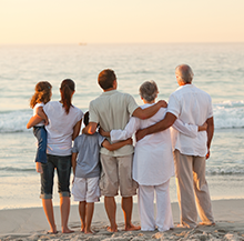 image of family standing on the beach embracing and watching the sunset