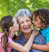 image of a grandma getting kissed by grand children on both cheeks
